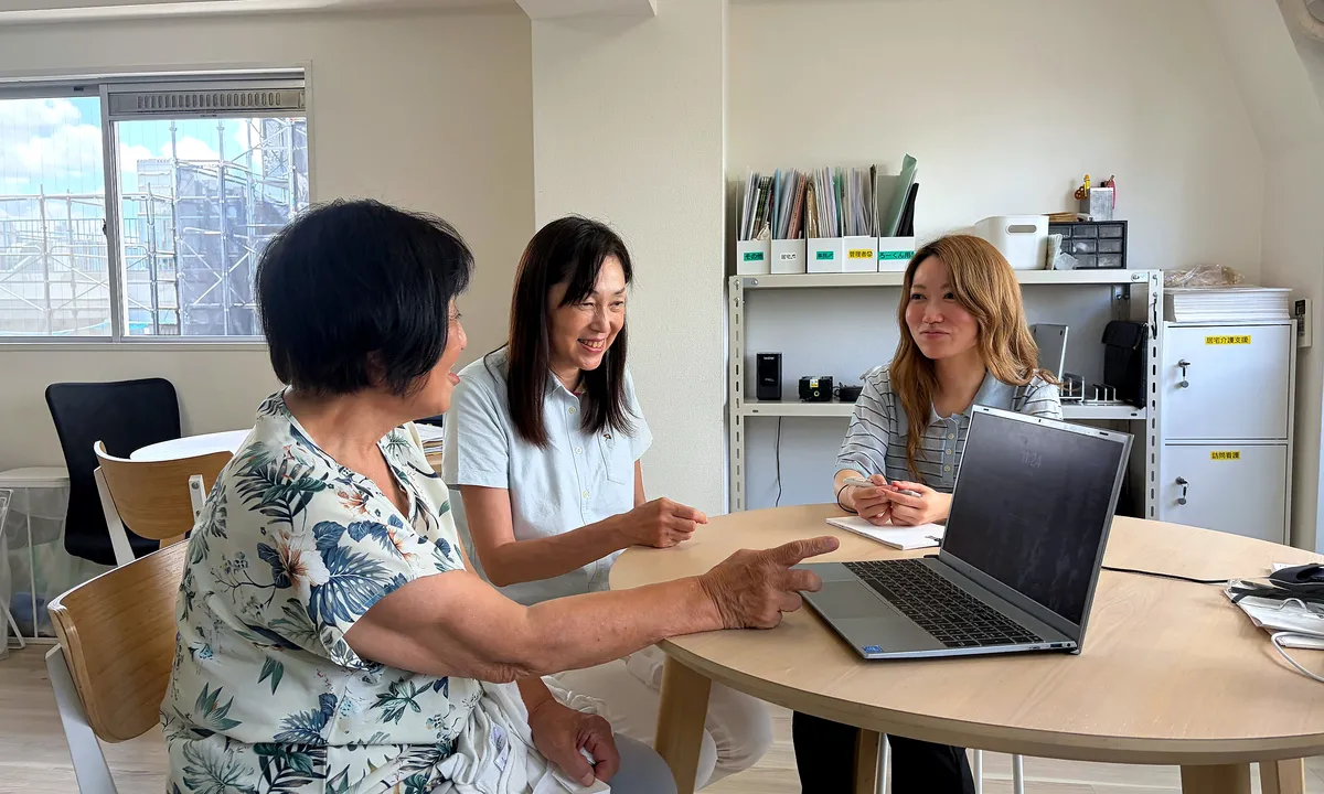 事務所の丸テーブルで打ち合わせをするケアマネジャーたち