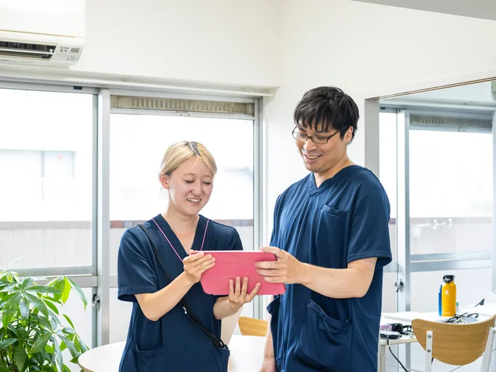 タブレットを見ながら業務内容を一緒に確認する訪問看護スタッフ2人